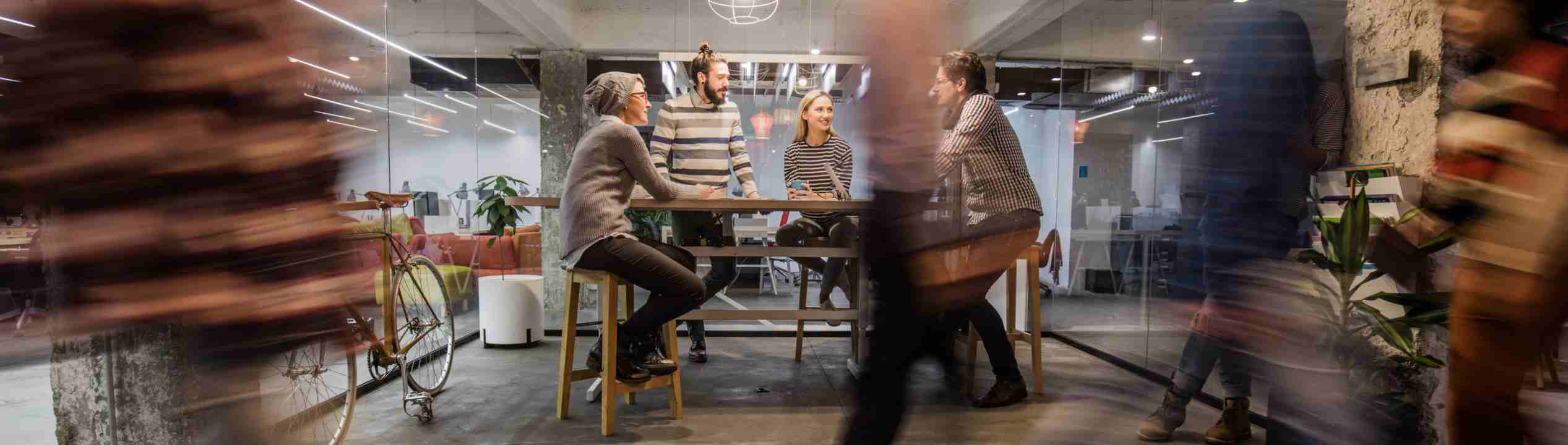 coworkers planning around a table while others walk by